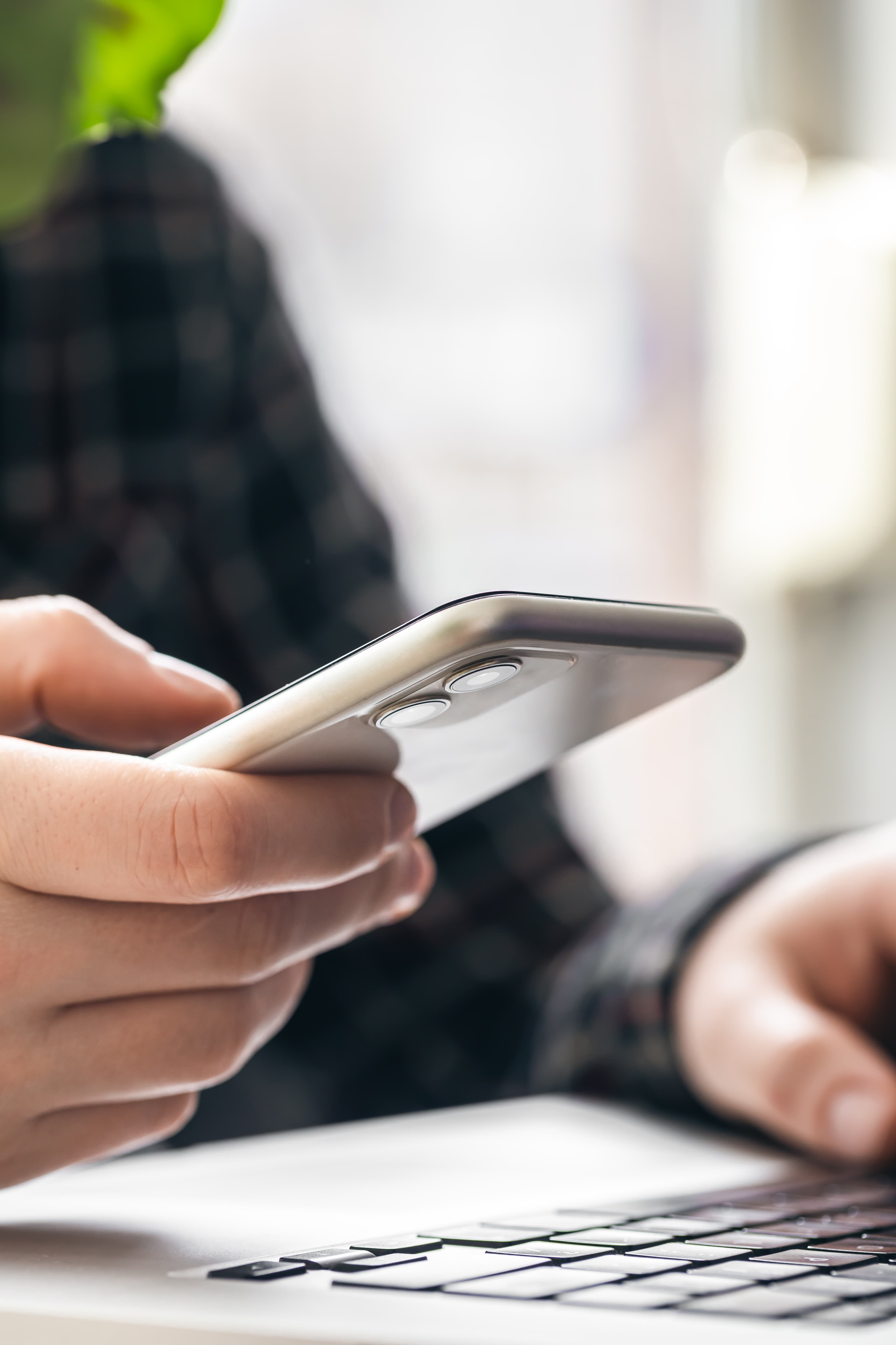 main tenant un smartphone à côté d'un ordinateur portable, symbole du démarchage téléphonique encadré par la loi 2026